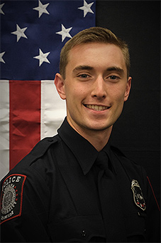 Reece Thompson in uniform in front of vertical United States flag